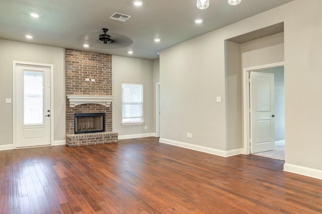 unfurnished living room with a brick fireplace, dark hardwood / wood-style floors, and ceiling fan