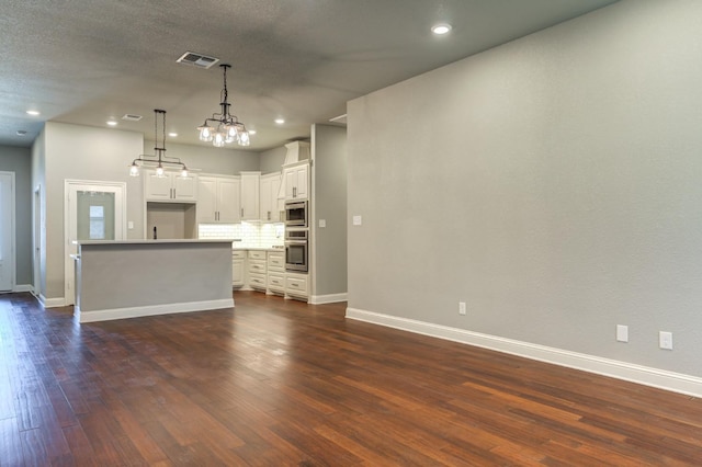 kitchen featuring tasteful backsplash, hanging light fixtures, a kitchen island, stainless steel appliances, and white cabinets