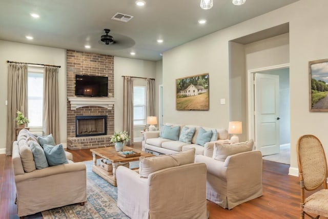 living room featuring hardwood / wood-style floors, a fireplace, ceiling fan, and plenty of natural light