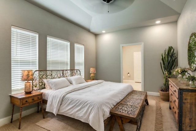 bedroom with ceiling fan, light colored carpet, and ensuite bath