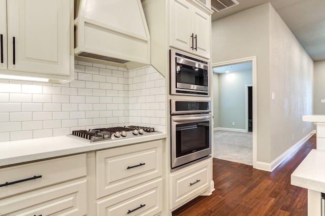 kitchen with premium range hood, appliances with stainless steel finishes, tasteful backsplash, light stone countertops, and dark wood-type flooring