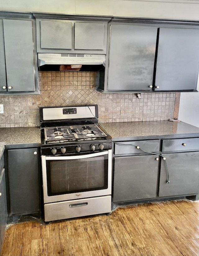 kitchen with stainless steel gas stove, tasteful backsplash, gray cabinetry, and light hardwood / wood-style floors