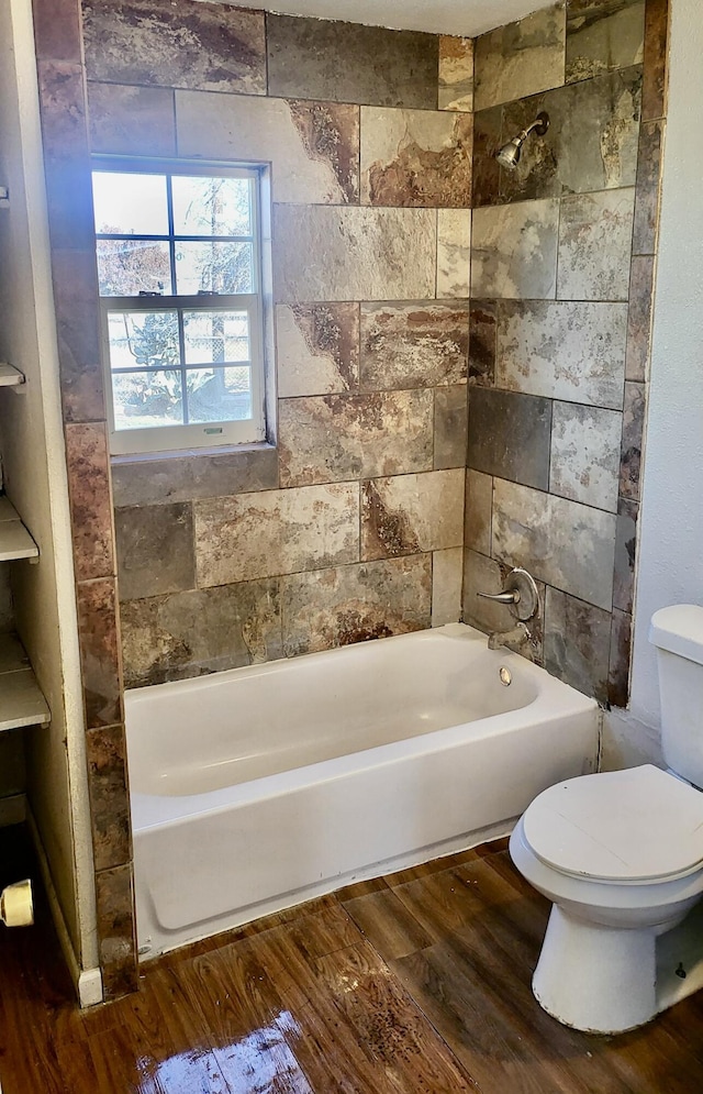 bathroom with tiled shower / bath, hardwood / wood-style floors, and toilet