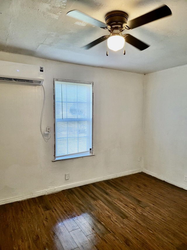 spare room featuring dark hardwood / wood-style floors, an AC wall unit, and ceiling fan