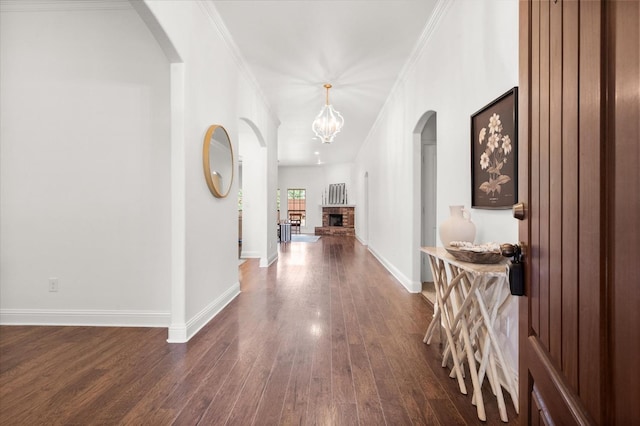 corridor with ornamental molding, dark wood-type flooring, and a notable chandelier