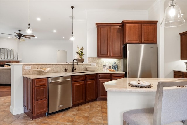 kitchen with appliances with stainless steel finishes, backsplash, a kitchen breakfast bar, ornamental molding, and decorative light fixtures