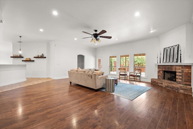 living room with ceiling fan, crown molding, hardwood / wood-style floors, and a fireplace