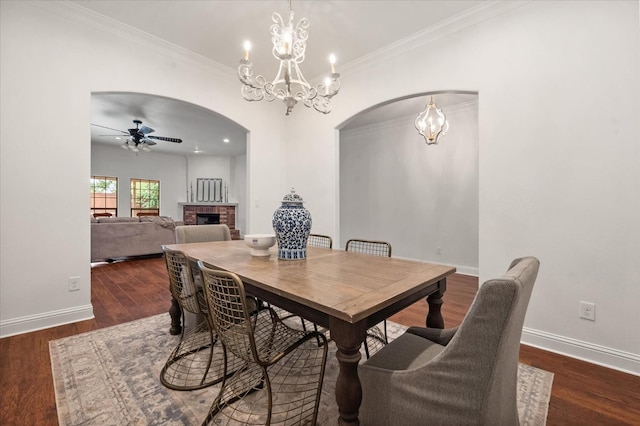 dining room featuring a fireplace, ornamental molding, dark hardwood / wood-style floors, and ceiling fan with notable chandelier