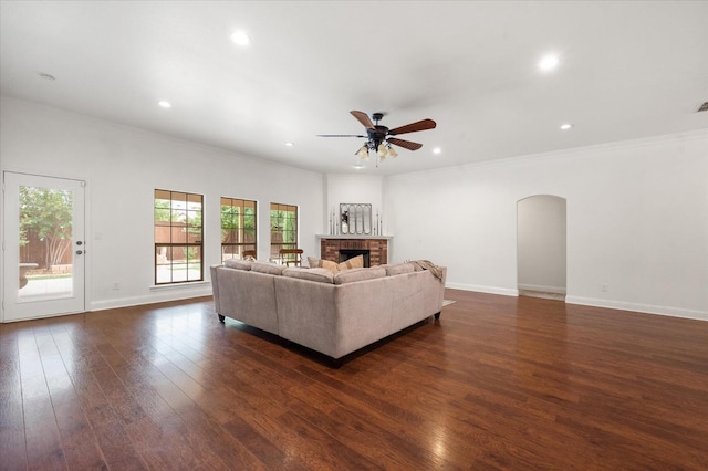 unfurnished living room featuring ornamental molding, a brick fireplace, dark wood-type flooring, and ceiling fan