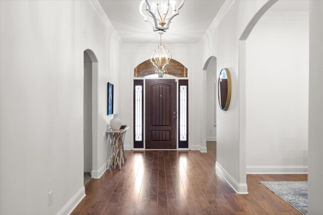 entryway with dark hardwood / wood-style flooring, ornamental molding, and a chandelier