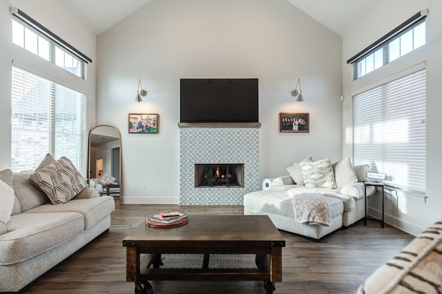 living room with dark hardwood / wood-style flooring, high vaulted ceiling, and a tile fireplace