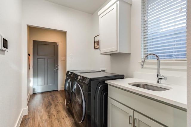 clothes washing area with independent washer and dryer, cabinets, sink, and light hardwood / wood-style flooring