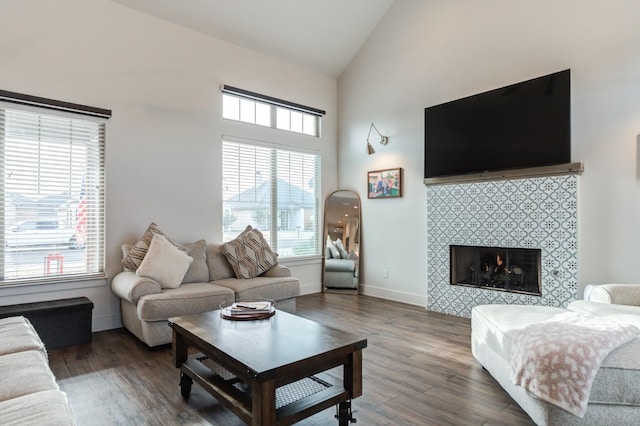 living room with a tile fireplace, dark wood-type flooring, and high vaulted ceiling