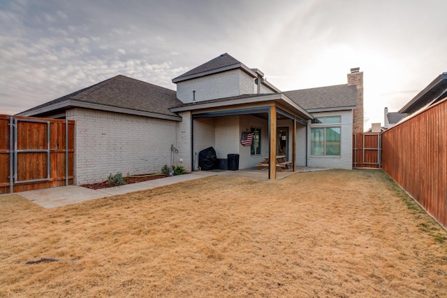 rear view of house with a lawn and a patio