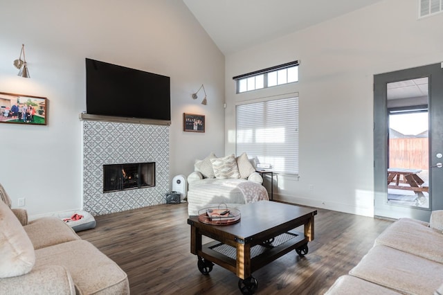 living room featuring dark wood-type flooring, high vaulted ceiling, and a tile fireplace