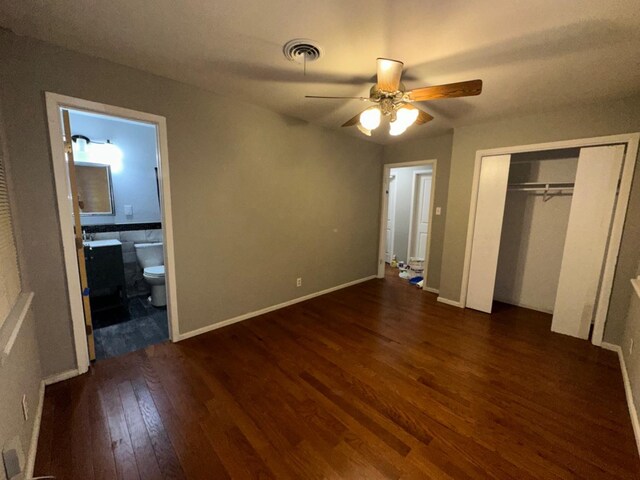 unfurnished bedroom featuring dark hardwood / wood-style flooring, connected bathroom, a closet, and ceiling fan