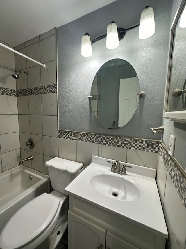 full bathroom featuring toilet, tasteful backsplash, tiled shower / bath, tile walls, and vanity