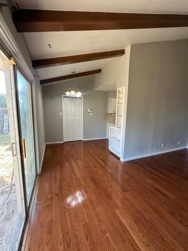 unfurnished room featuring an inviting chandelier, hardwood / wood-style floors, and beamed ceiling