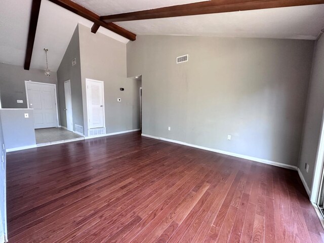 unfurnished living room featuring hardwood / wood-style floors, beam ceiling, and high vaulted ceiling