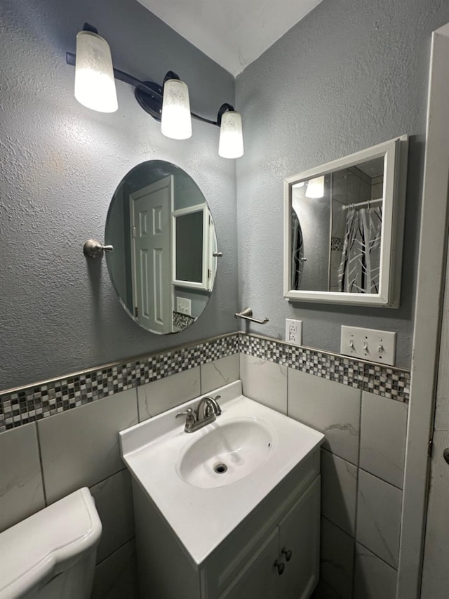 bathroom with vanity, tile walls, toilet, and walk in shower