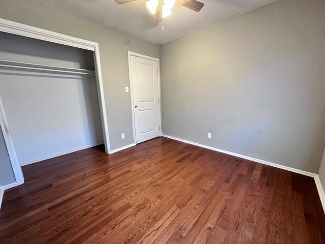 unfurnished bedroom with dark hardwood / wood-style floors, ceiling fan, and a closet