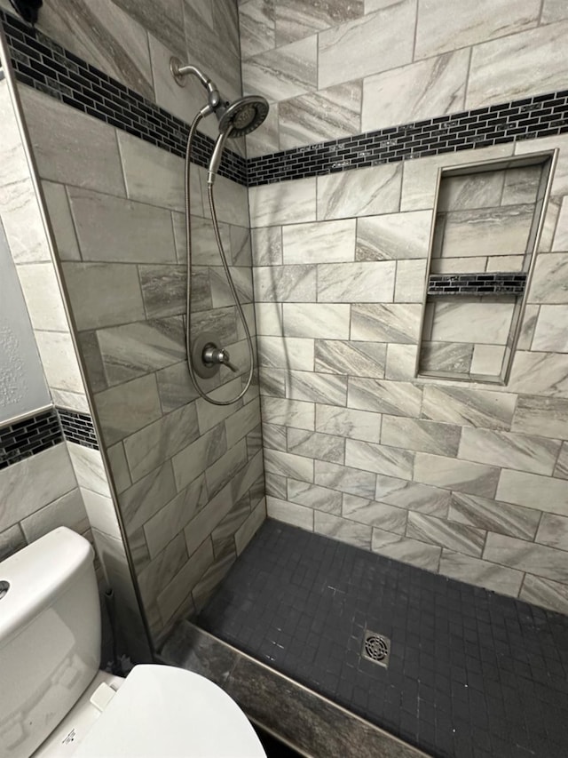 bathroom featuring a tile shower and toilet