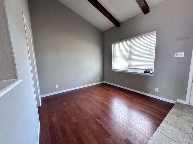 empty room with dark wood-type flooring and vaulted ceiling with beams