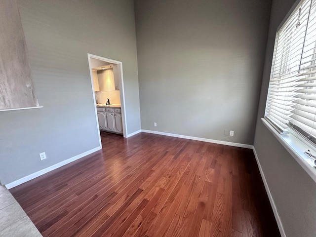 unfurnished room featuring a high ceiling and dark wood-type flooring