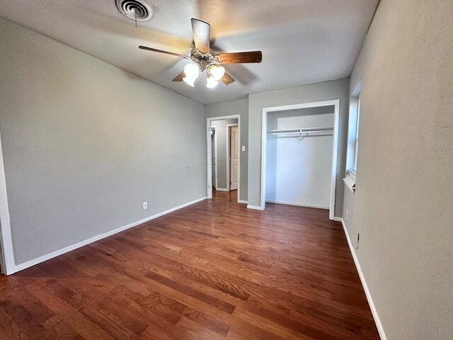 unfurnished bedroom with a closet, dark hardwood / wood-style floors, and ceiling fan