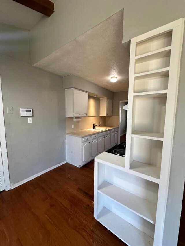 kitchen with built in features, white cabinetry, sink, dark hardwood / wood-style flooring, and a textured ceiling