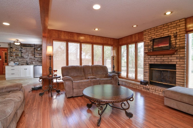 2911 US Highway 385, Littlefield, TX 79339 - living room featuring a fireplace, wood walls, a textured ceiling, and light wood-type flooring