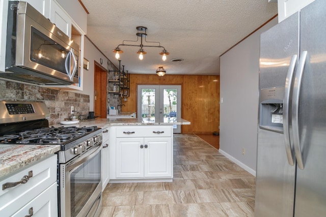 2911 US Highway 385, Littlefield, TX 79339 - kitchen featuring french doors, white cabinetry, kitchen peninsula, pendant lighting, and stainless steel appliances