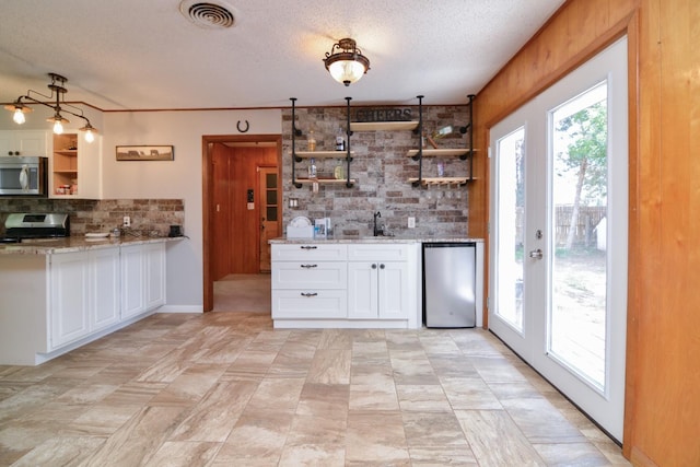 2911 US Highway 385, Littlefield, TX 79339 - kitchen with sink, stainless steel appliances, light stone counters, tasteful backsplash, and white cabinets