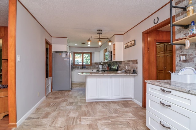 2911 US Highway 385, Littlefield, TX 79339 - kitchen featuring crown molding, backsplash, stainless steel appliances, light stone counters, and white cabinets