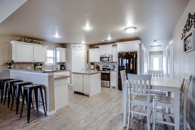 kitchen featuring sink, kitchen peninsula, white cabinets, and appliances with stainless steel finishes