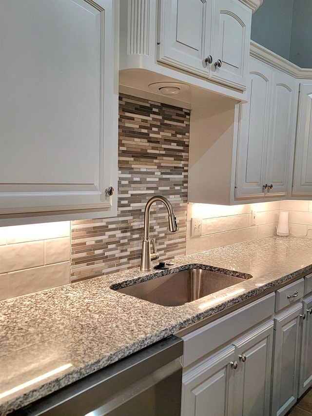 kitchen featuring backsplash, light stone countertops, sink, and white cabinets