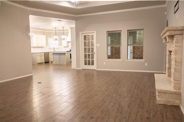 unfurnished living room with dark hardwood / wood-style flooring, sink, crown molding, and an inviting chandelier