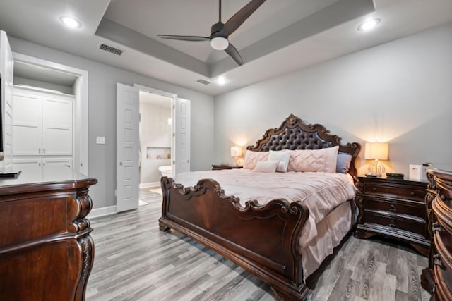 bedroom featuring hardwood / wood-style flooring, ceiling fan, and a tray ceiling