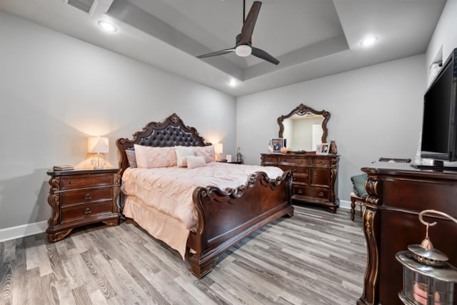 bedroom featuring a tray ceiling, light hardwood / wood-style flooring, and ceiling fan