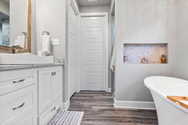 bathroom featuring hardwood / wood-style flooring, vanity, and a washtub