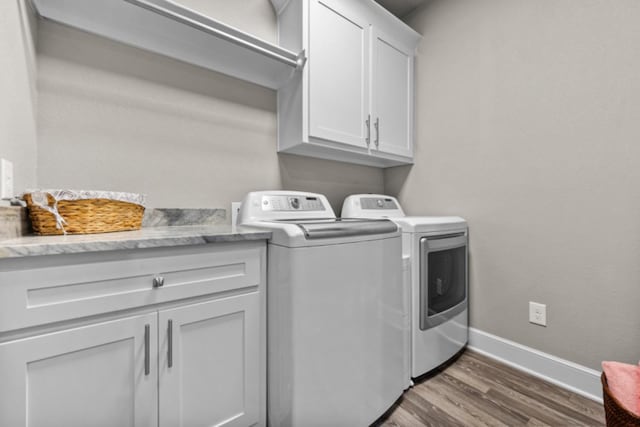 laundry area with dark hardwood / wood-style floors, washer and clothes dryer, and cabinets