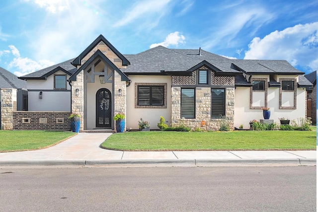 view of front facade featuring stone siding, a shingled roof, and a front lawn