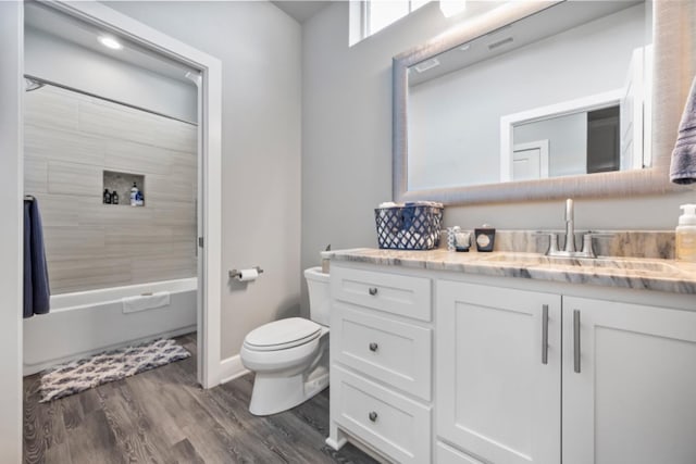 full bathroom featuring vanity, hardwood / wood-style floors, tiled shower / bath combo, and toilet