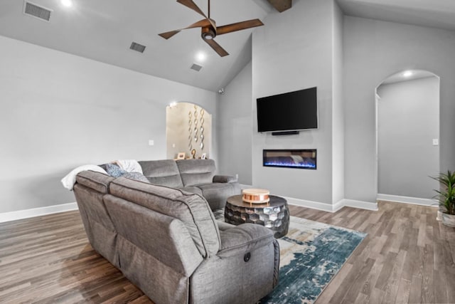 living room with ceiling fan, wood-type flooring, beam ceiling, and high vaulted ceiling