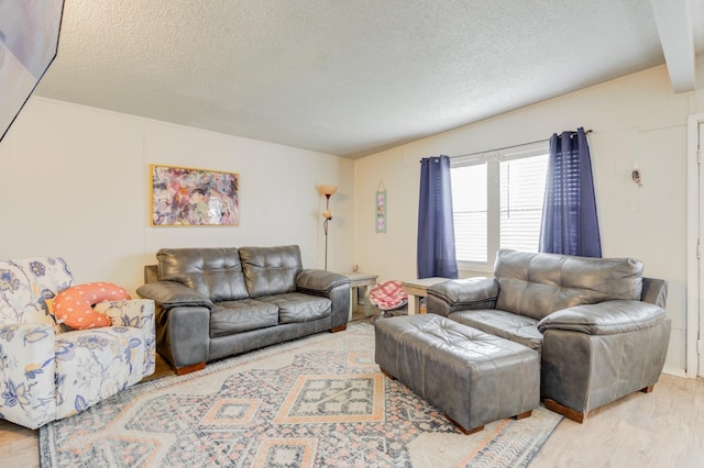 living room featuring beamed ceiling, light hardwood / wood-style floors, and a textured ceiling