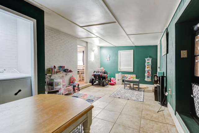 bathroom with tile patterned flooring, washer / dryer, and brick wall