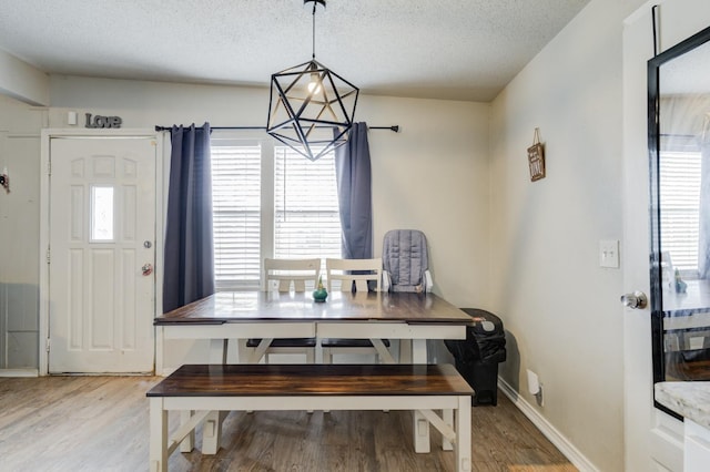 dining room with hardwood / wood-style flooring, a textured ceiling, and a notable chandelier