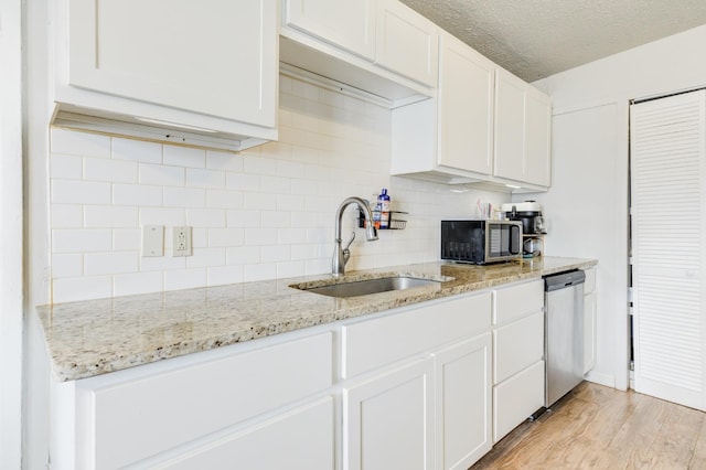 kitchen with sink, white cabinetry, a textured ceiling, appliances with stainless steel finishes, and light stone countertops