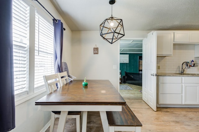 dining room with sink, light hardwood / wood-style floors, and a textured ceiling