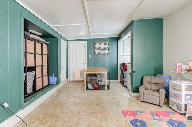 playroom featuring washer / dryer and brick wall